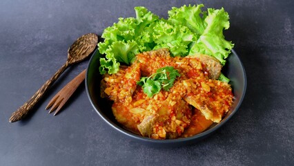 Top view  sea bass snapper fillet with garlic chilli spicy sauce on black background, Thai style food.