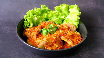 Top view  sea bass snapper fillet with garlic chilli spicy sauce on black background, Thai style food.