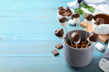 Delicious marshmallows covered with chocolate on blue wooden table. Space for text
