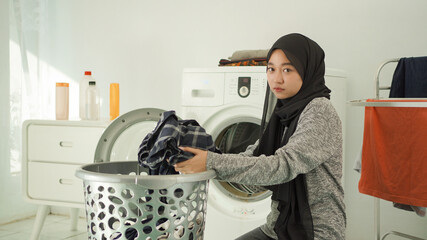 young asian woman taking dirty clothes to wash with a gloomy face at home