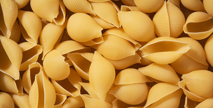 Background of pasta conchiglioni made from durum wheat. Healthy vegan food. Top view and pattern