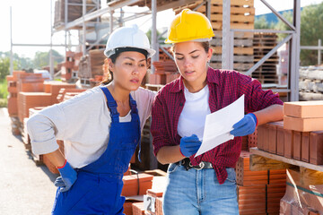 Two women keep track of the number of bricks at the site of hardware store