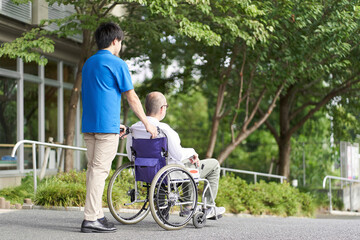車椅子の高齢者をサポートする介護士