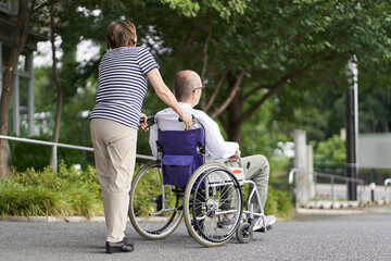 車椅子の高齢者をサポートする家族