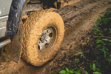 Fototapeta na wymiar Part of the muddy off-road wheels On a muddy road in the evergreen forest adventure concept forest tourism concept