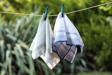 Different handkerchiefs hanging on rope against blurred background