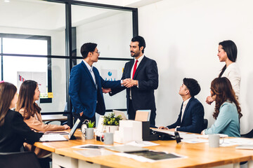 Image two asian business partners in elegant suit successful handshake together in front of group of casual business clapping hands in modern office.Partnership approval and thanks gesture concept