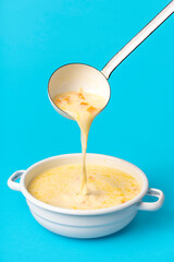 Greek soup in a white enamel bowl. Pouring soup from the ladle