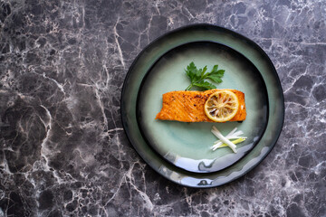 Top view of Salmon fish fillet cooked with different spices and served on plate.