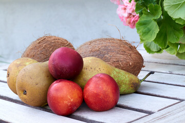Isolated collection of fruits consisting of coconuts, pears and nectarines on a wooden table