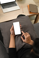 Overhead shot man sitting on couch and using smart phone.