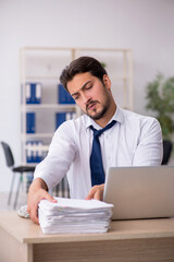 Naklejka premium Young male employee unhappy with excessive work in the office