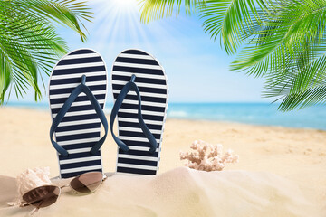 Fototapeta na wymiar Striped flip flops, coral, sea shell and sunglasses on sandy beach