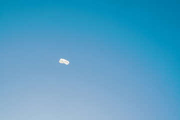 flying empty white plastic bag in front of blue sky