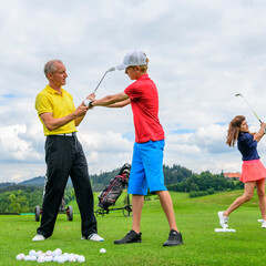 Junger Golfspieler beim Training mit Pro auf der Driving-Range