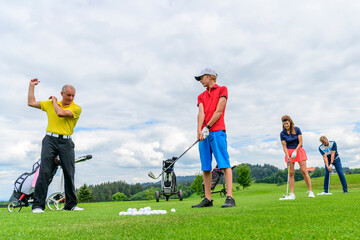 Obraz na płótnie Canvas Golf-Schüler beim Training mit Pro auf der Driving-Range