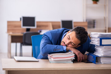 Young male employee unhappy with excessive work at workplace