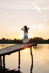 Anonymous woman standing on pier in warm sunset light  - 455220508