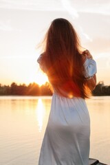 Anonymous woman with long beautiful hair posing at sunset  - 455220585