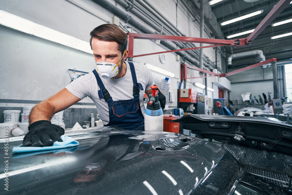 Sticker car cleaning performed by auto mechanic in workshop