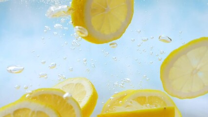 Slow Motion of fresh yellow lemon slices falling into water splash on blue background, Vegetables for health. - Powered by Adobe