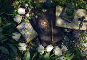 Wicca ritual with beautiful roses, tarot cards, grimoire book and magic objects.