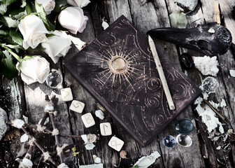 Grunge still life with witch book, pentagram, runes and roses on planks.
