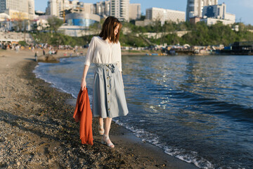 Woman in dress enjoys the sea shore.