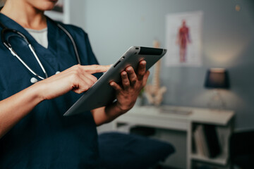 Close up female doctor researching in clinic typing on digital tablet