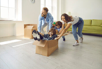 Happy family having fun in new home. Joyful excited first-time buyers with children playing with cardboard boxes in living room interior. Real estate, residential mortgage, buying dream house concept