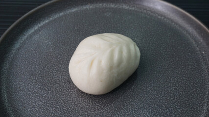 steamed fresh yellow corn custard bun white baozi in leaf shape on dark grey wood background dim sum halal menu
