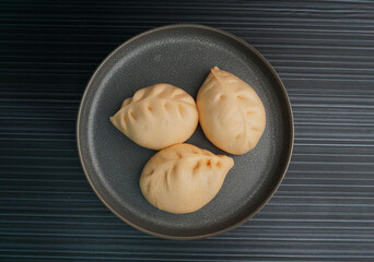 steamed fresh curry potato vegan bun orange baozi in leaf shape on dark grey wood background dim sum halal menu