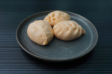 Chinese Hong Kong steamed fresh curry potato bun vegan orange bao zi in leaf shape on dark grey wood background asian dim sum halal food restaurant cuisine banquet menu for cafe
