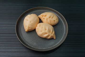 steamed fresh curry potato vegan bun orange baozi in leaf shape on dark grey wood background dim sum halal menu