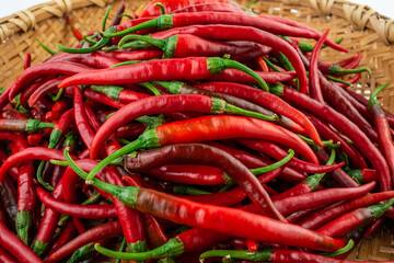 Bamboo sieve filled with fresh red peppers on white background