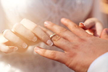 Obraz na płótnie Canvas Bride and groom hands together and bride put wedding ring to grooms hand as a symbol of bonding