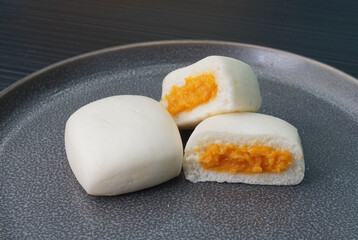 Chinese Hong Kong steamed fresh mini lava cheese salted egg yolk custard bun vegan bao zi in leaf shape on dark grey wood table asian dim sum halal food restaurant cuisine banquet menu for cafe