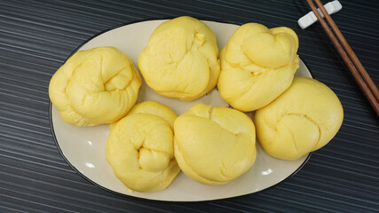 Chinese Hong Kong steamed fresh yellow pumpkin mantou bun vegan green bao in leaf shape on dark...