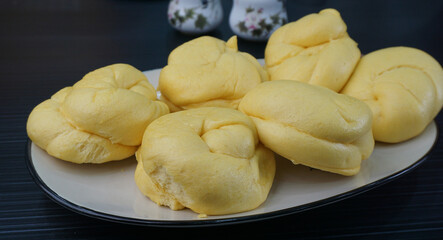 Chinese Hong Kong steamed fresh yellow pumpkin mantou bun vegan green bao in leaf shape on dark grey wood background asian dim sum halal food restaurant cuisine banquet menu for cafe