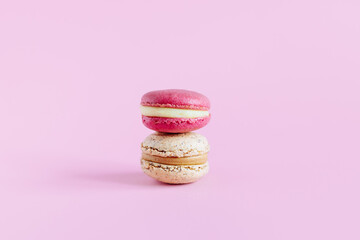 Tasty french macarons on a pink pastel background.