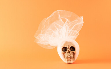 Sugar skull with white vail against orange background. Creative halloween or day of the dead concept.  Copy space. - obrazy, fototapety, plakaty