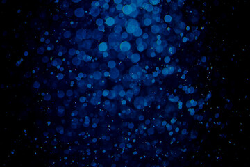 Glittering stars of blue bokeh on black background
