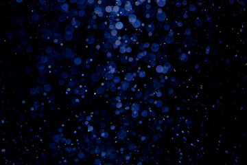 Glittering stars of blue bokeh on black background