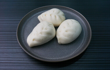 Chinese Hong Kong steamed fresh mixed vegetables carrot bun vegan white bao zi in leaf shape on dark grey wood background asian dim sum halal food restaurant cuisine banquet menu for cafe
