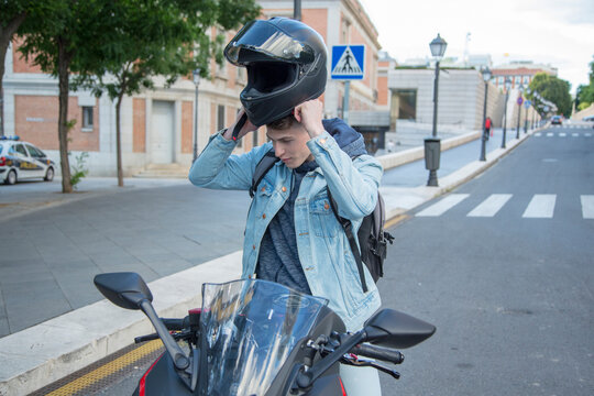 Young Man Riding A Motorcycle Putting On Helmet In City