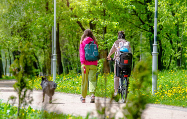 Two girls with a child and a dog are walking in the park
