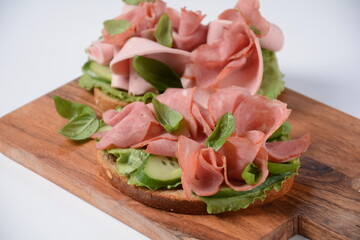 Open ham Sandwich with cucumbers, basil, and a crusty slice of rye bread and salami