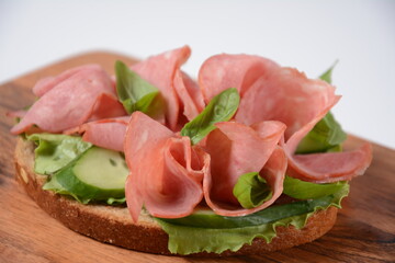 Open ham Sandwich with cucumbers, basil, and a crusty slice of rye bread and salami