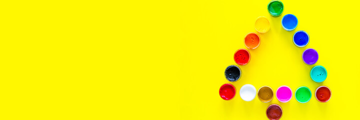 Creative Christmas tree made of paint cans on a yellow background with a place for text. top view, flat lay, copy space, isolate