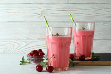 Glasses of cherry smoothie and ingredients on white wooden table